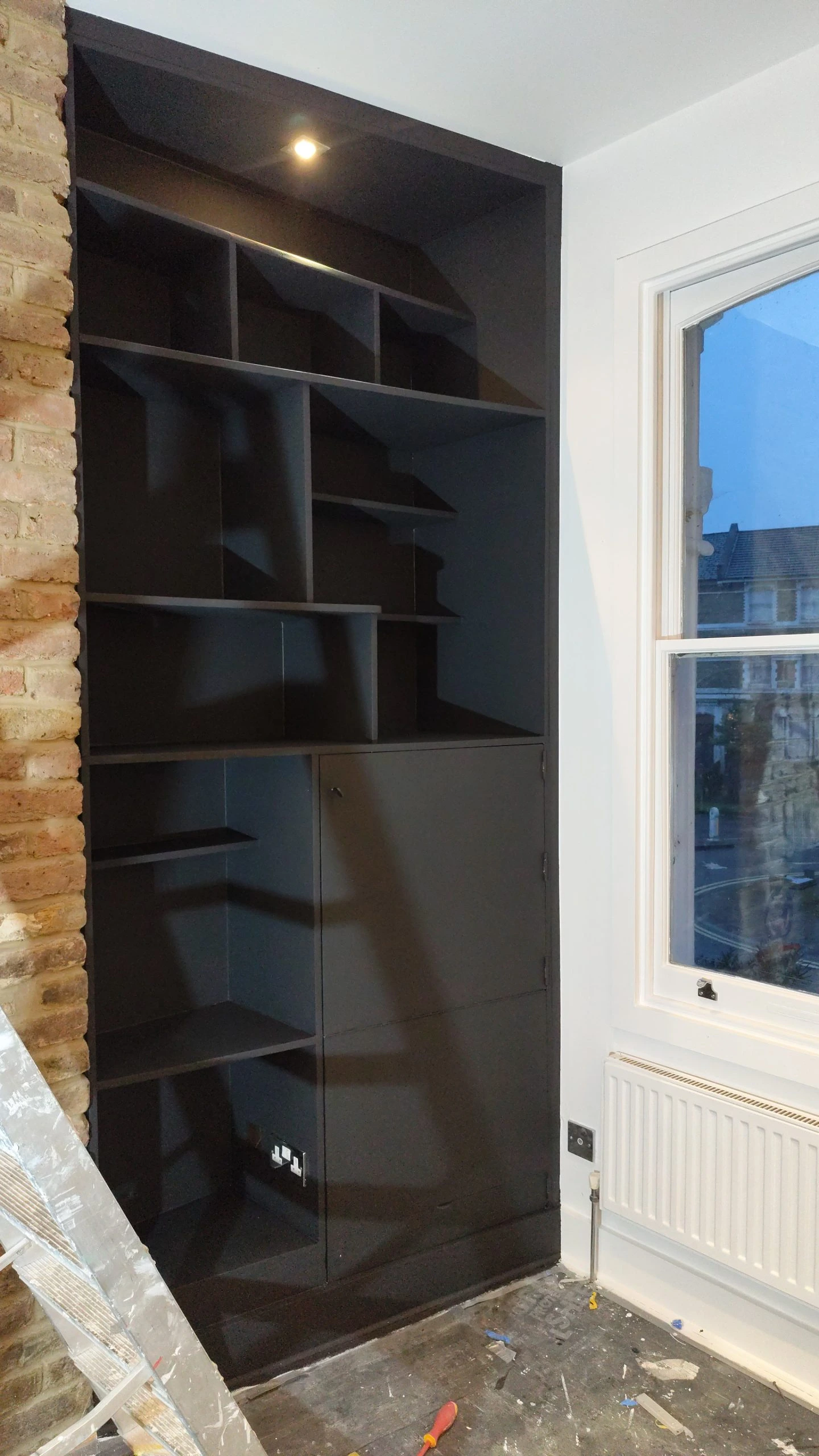 Black built-in shelving unit with cabinet storage and spotlight lighting in Camden renovation