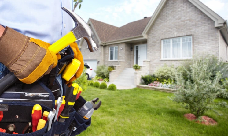 Reliable handy man in London with tool belt and hammer standing in front of a residential home ready for property repairs