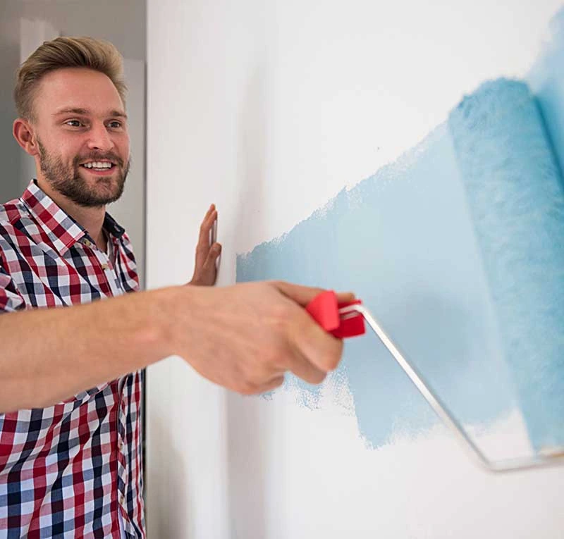 Handyman painting a wall with a roller during interior home maintenance work