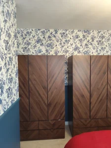 Blue floral wallpaper bedroom with wooden wardrobes and navy wall panelling in South East London