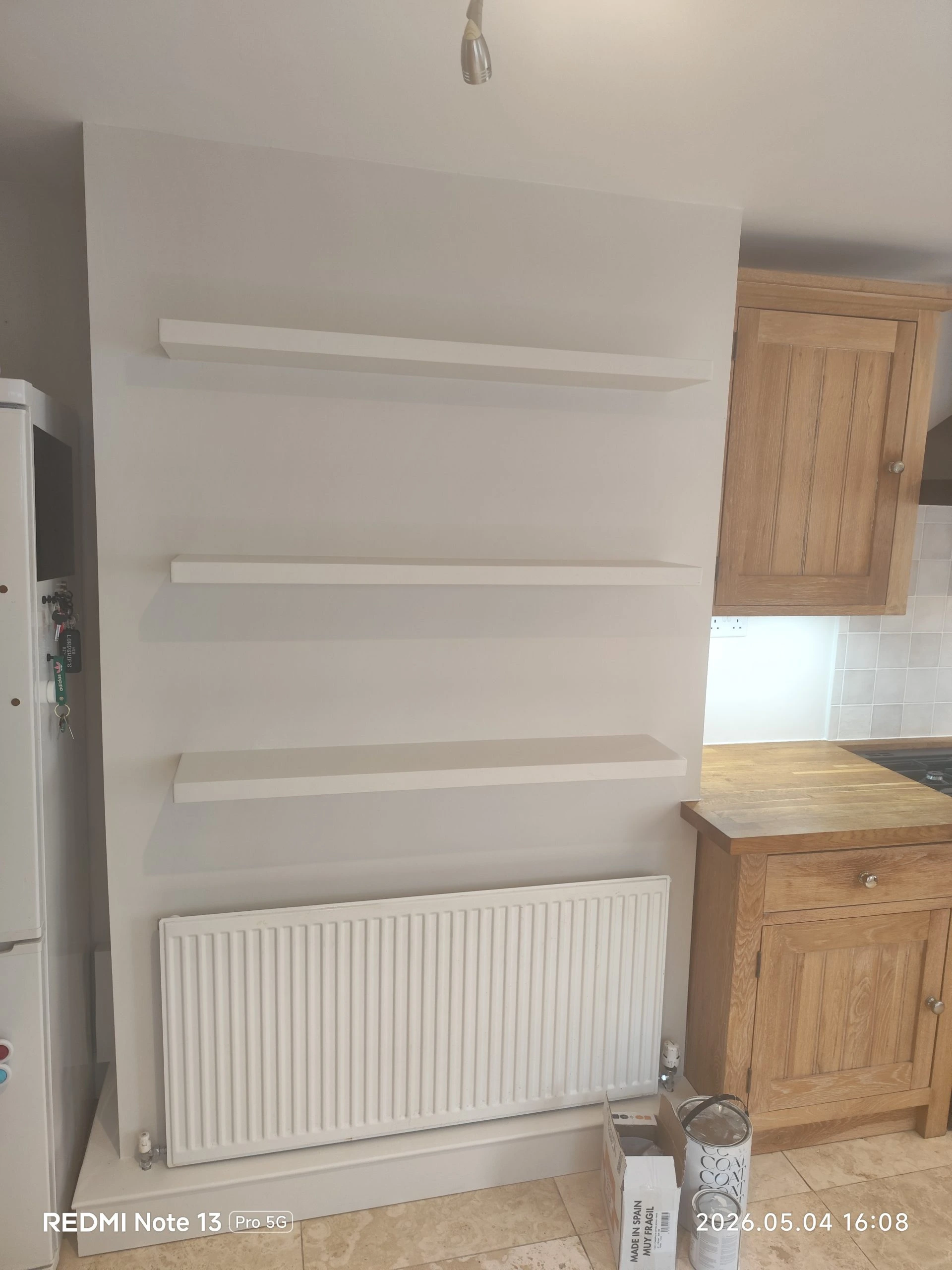 Wall painting with floating shelves installation above radiator in kitchen